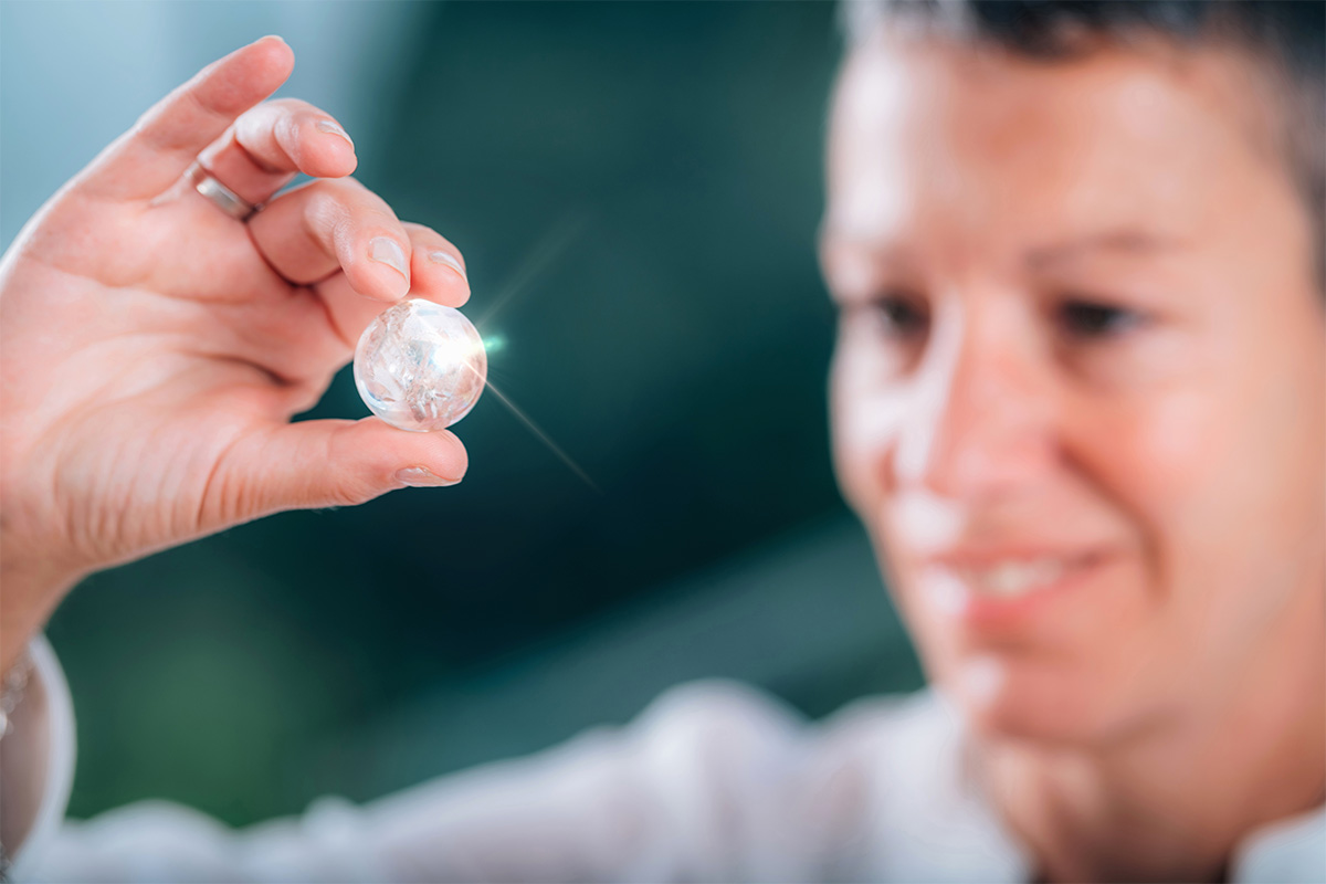 White 50-year-old woman holding up a gem into the light.