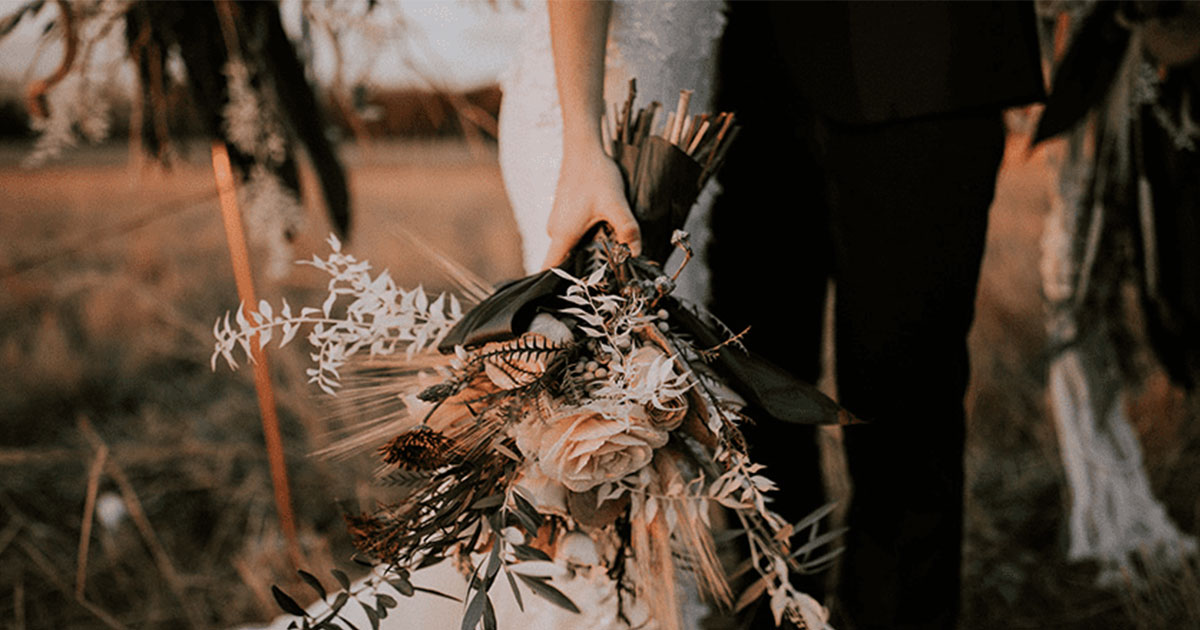 bride holding bouquet in field