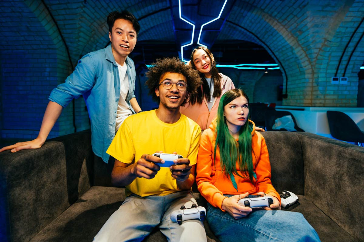 Diverse group of young friends playing video games on a couch