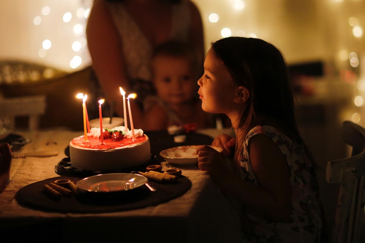  A little white girl blowing out candles on a cake 