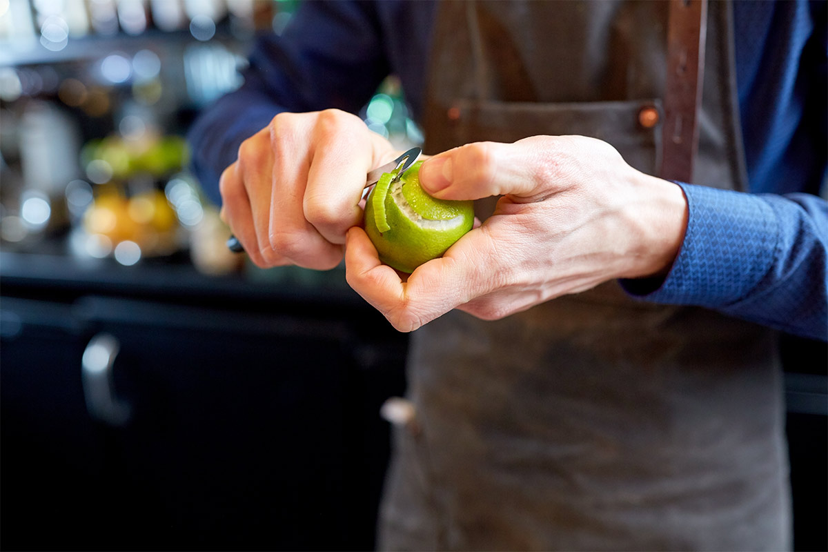 Man peeling a lime in a bar setting 