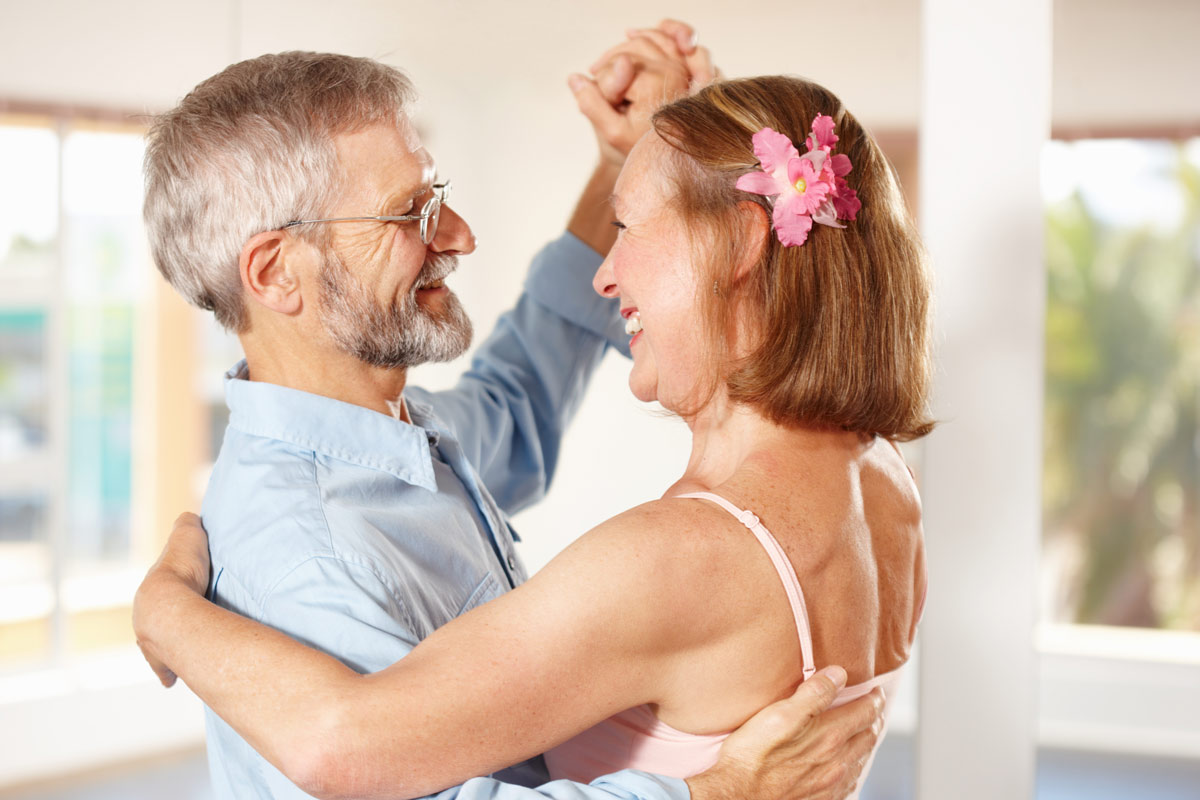 ginger bride dancing happily with older father while indoors 