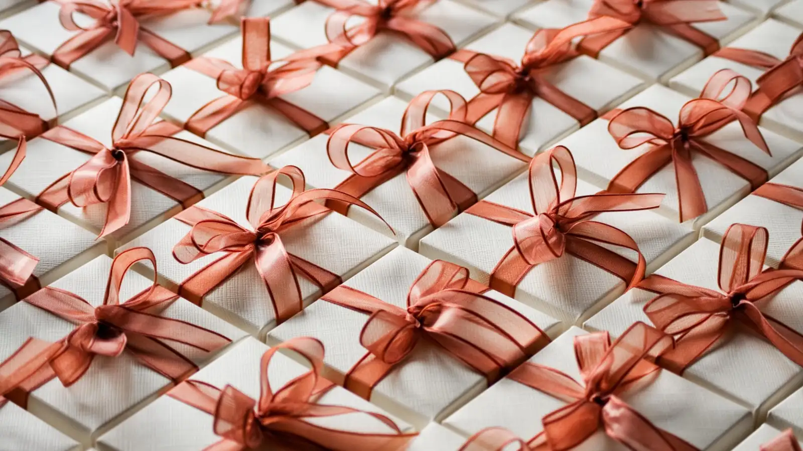 Neatly wrapped bar mitzvah party favors with white boxes and copper ribbon bows arranged in rows