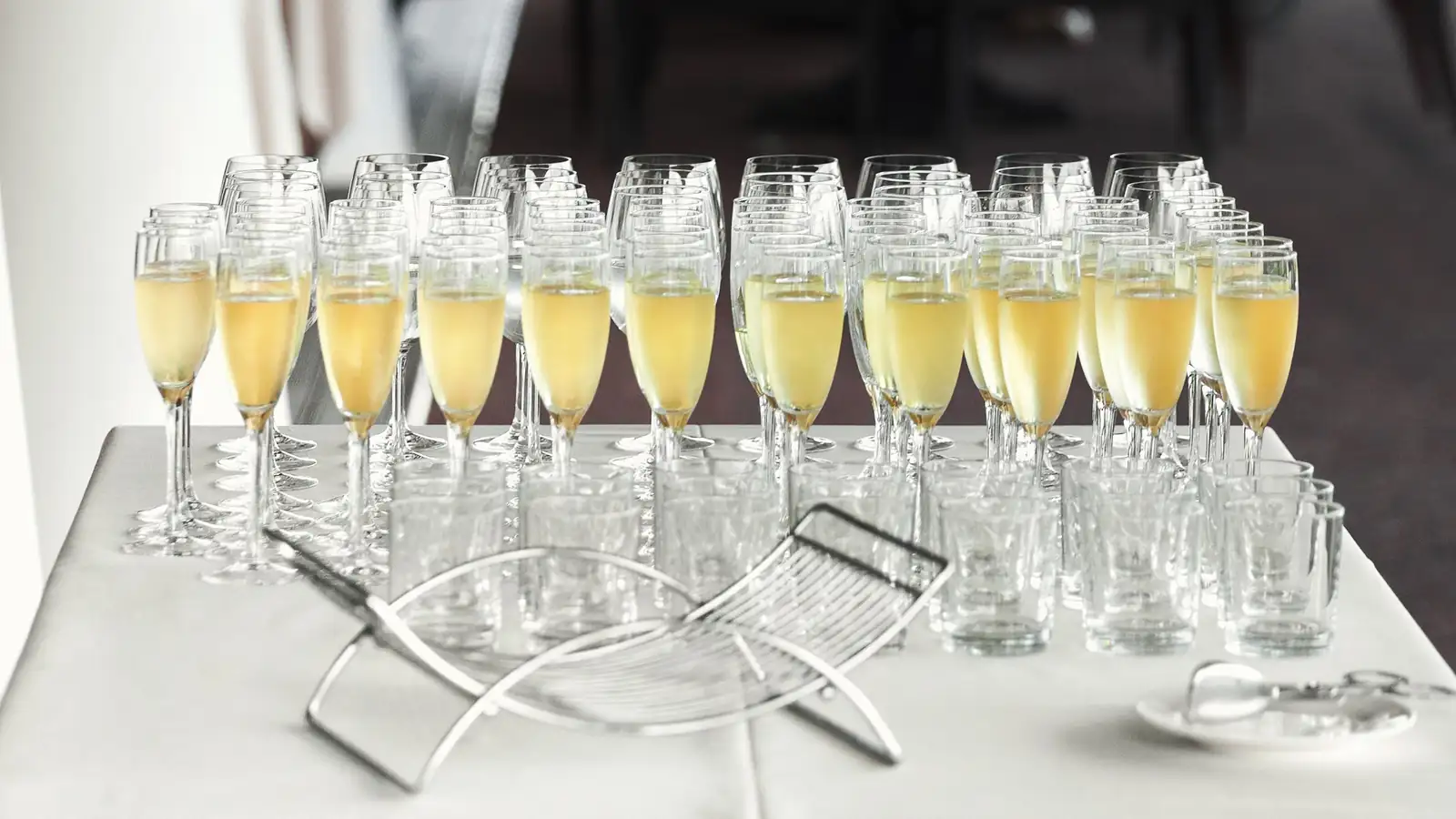 Champagne flutes filled with sparkling wine arranged on a table for a black tie party