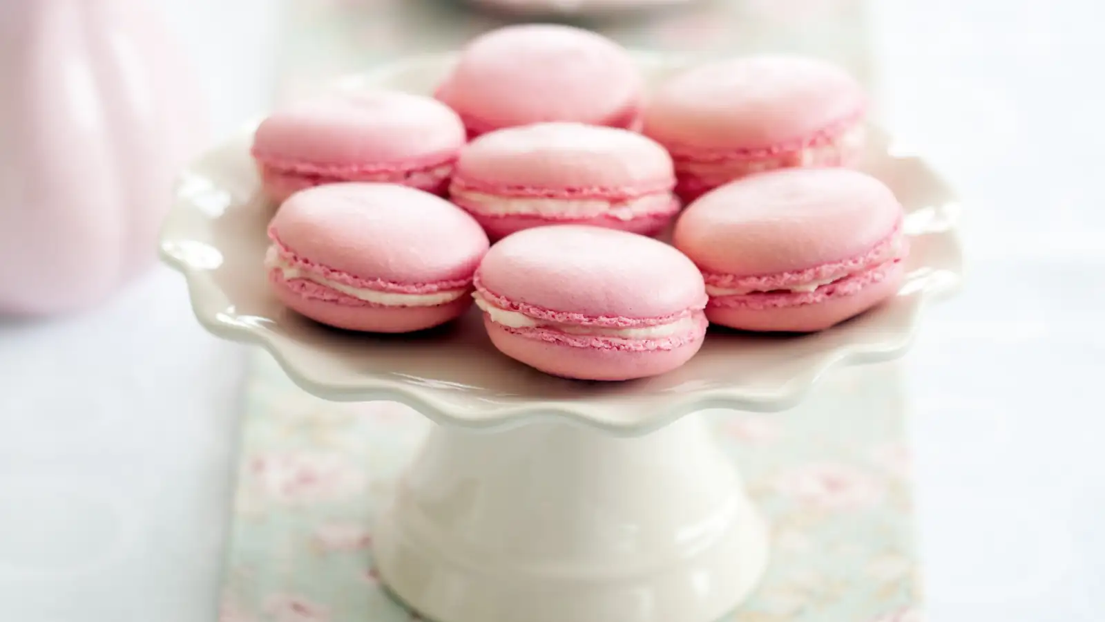 Pink macarons displayed on a cake stand for a bonjour bébé baby shower