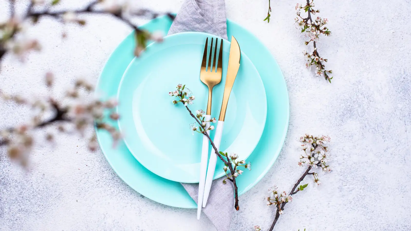 Tiffany blue place setting with gold flatware and spring blossoms for a Breakfast at Tiffany’s themed party