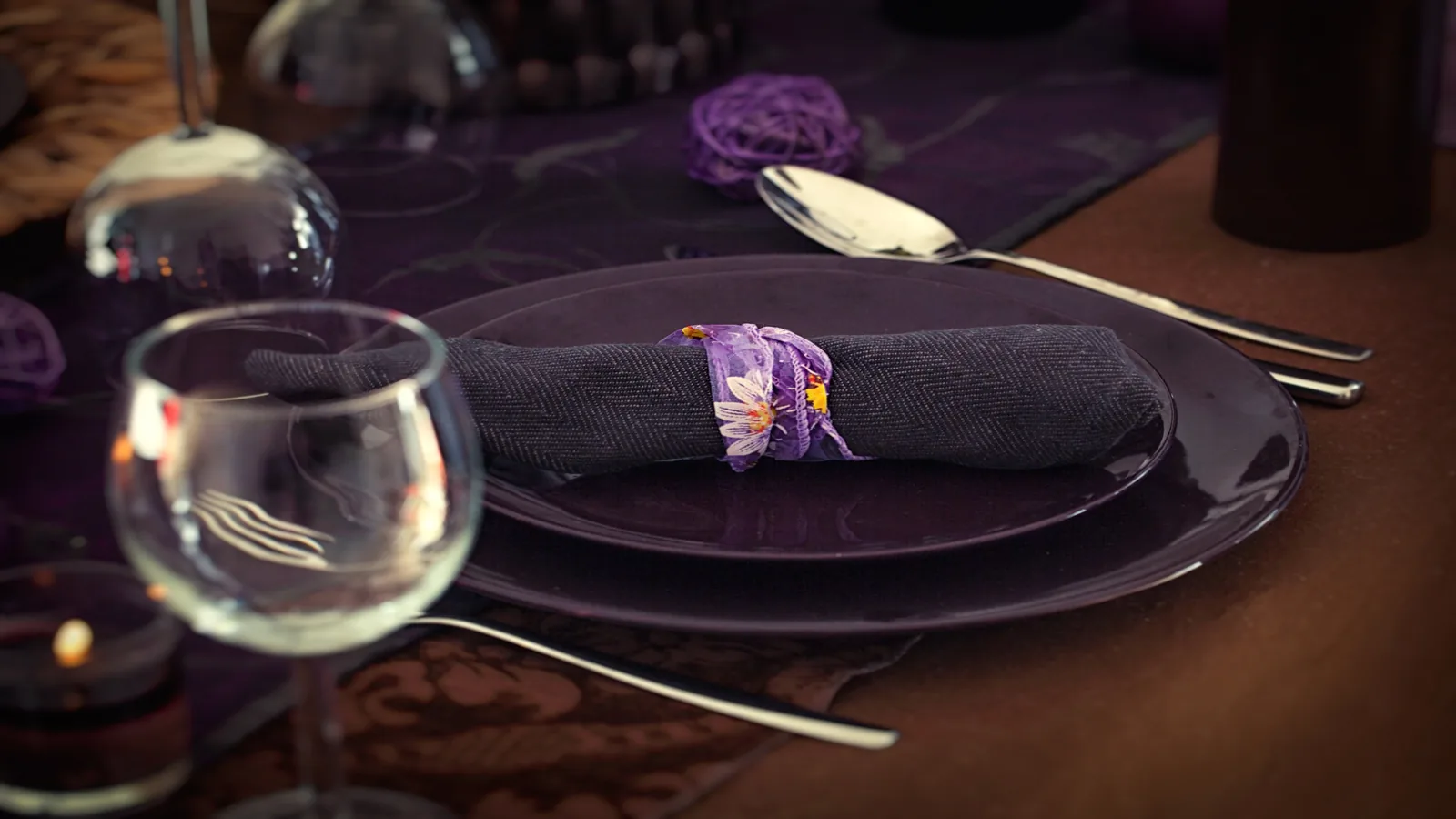 Purple color party table setting with deep purple plates, dark linens, glassware, and elegant moody styling