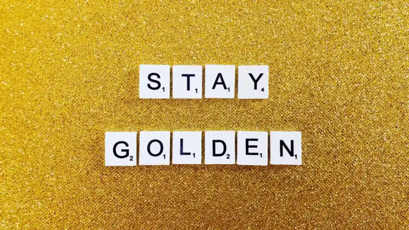 Golden birthday quote display spelling 'stay golden' with letter tiles on a glittery gold background