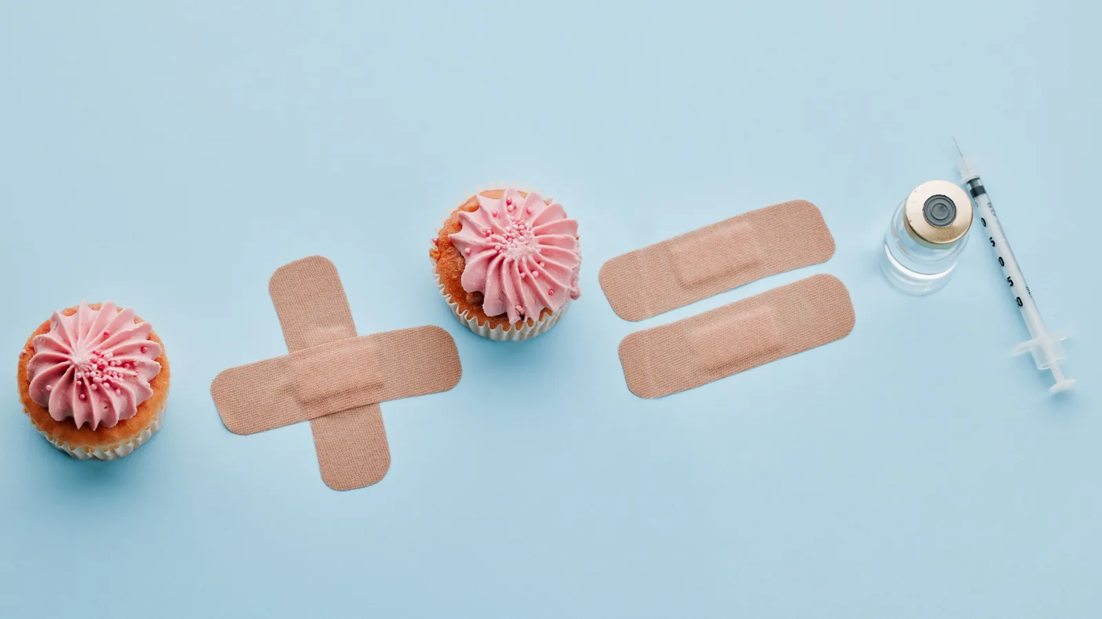 Medical party ideas featuring cupcakes styled with bandages and medical symbols alongside a syringe on a light blue background