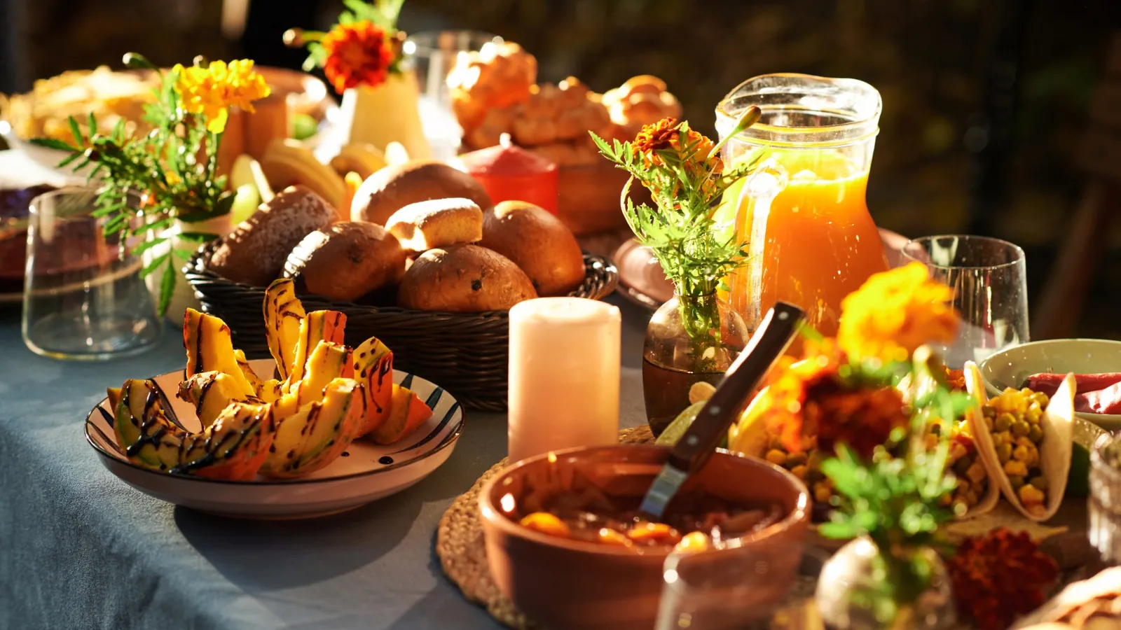 Medieval themed party feast with rustic bread, roasted vegetables, wooden serving dishes, candles, and warm candlelight