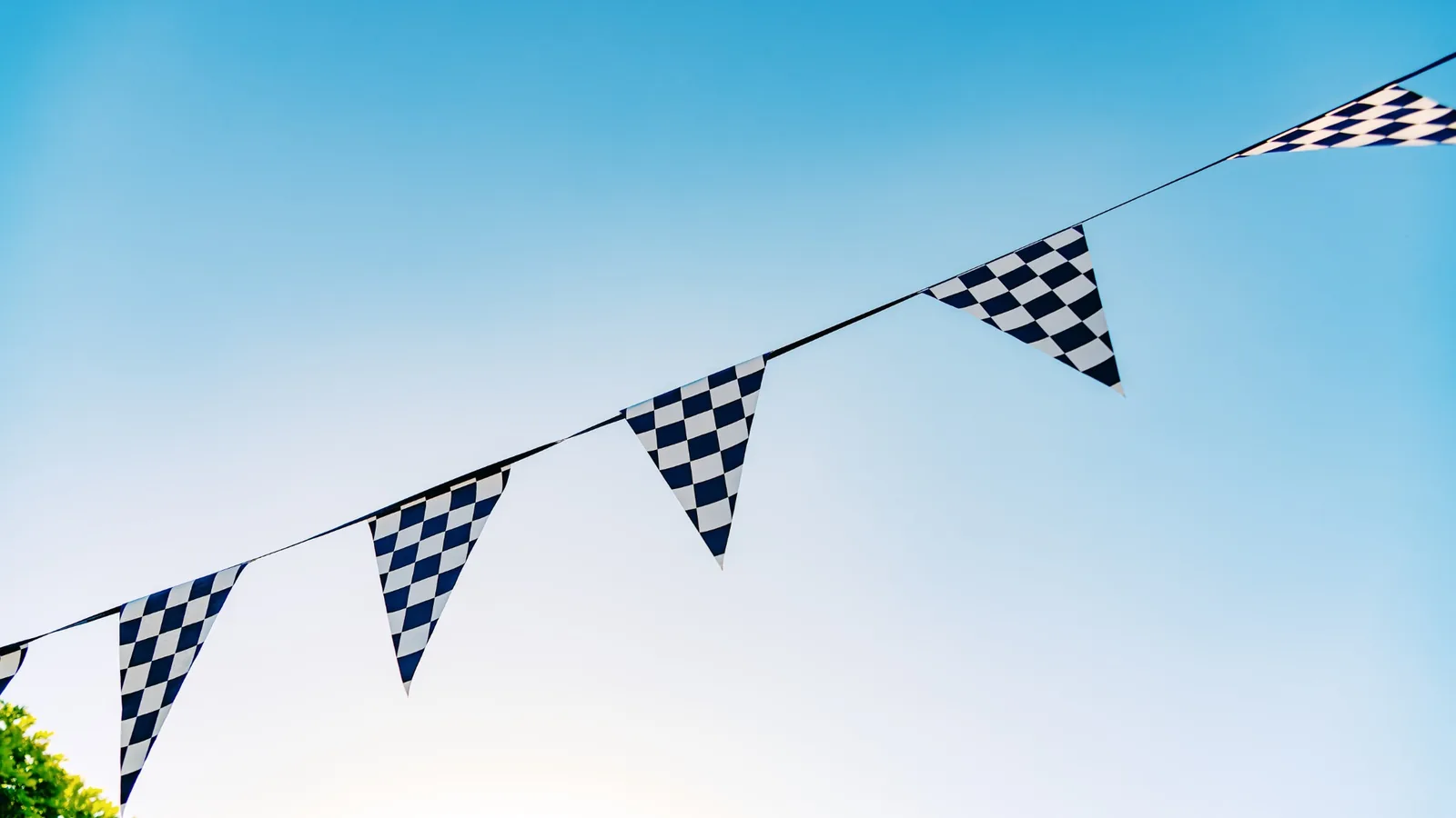Black and white checkered racing flags strung across the sky as decoration for a race car themed party