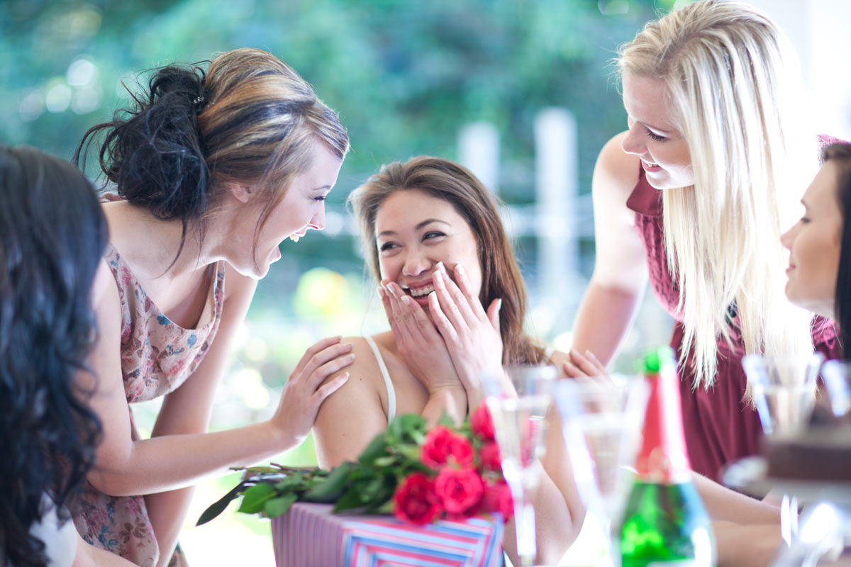 Five white women engaged in laughter and merriment, celebrating together at a lively party.