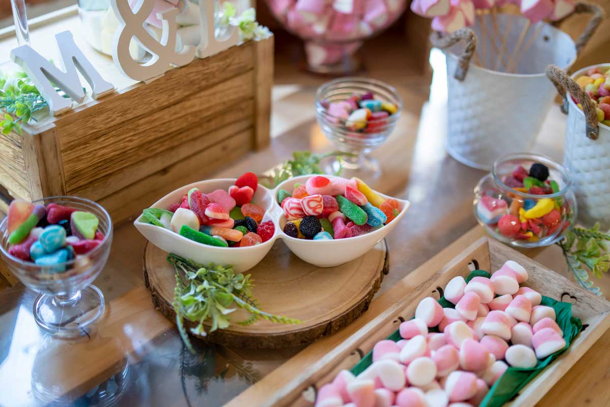 Colorful candy bar with glass jars of assorted sweets, adding a playful element to the wedding reception.