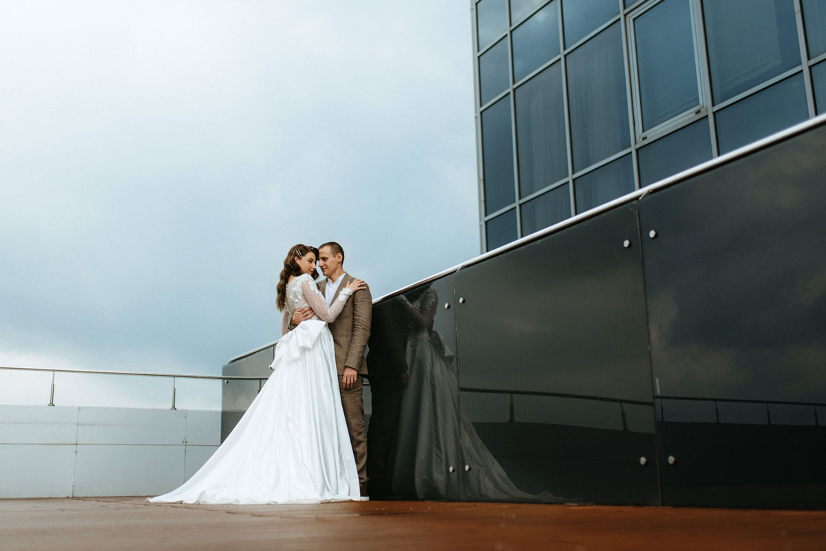 30 something white bride and groom’s first look on a rooftop with city skyline backdrop