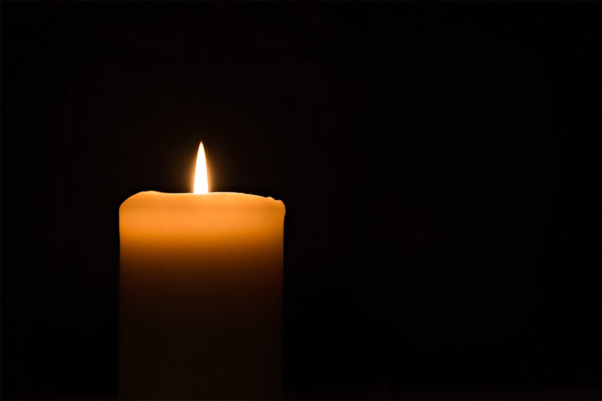 a single large candle burning with a black background