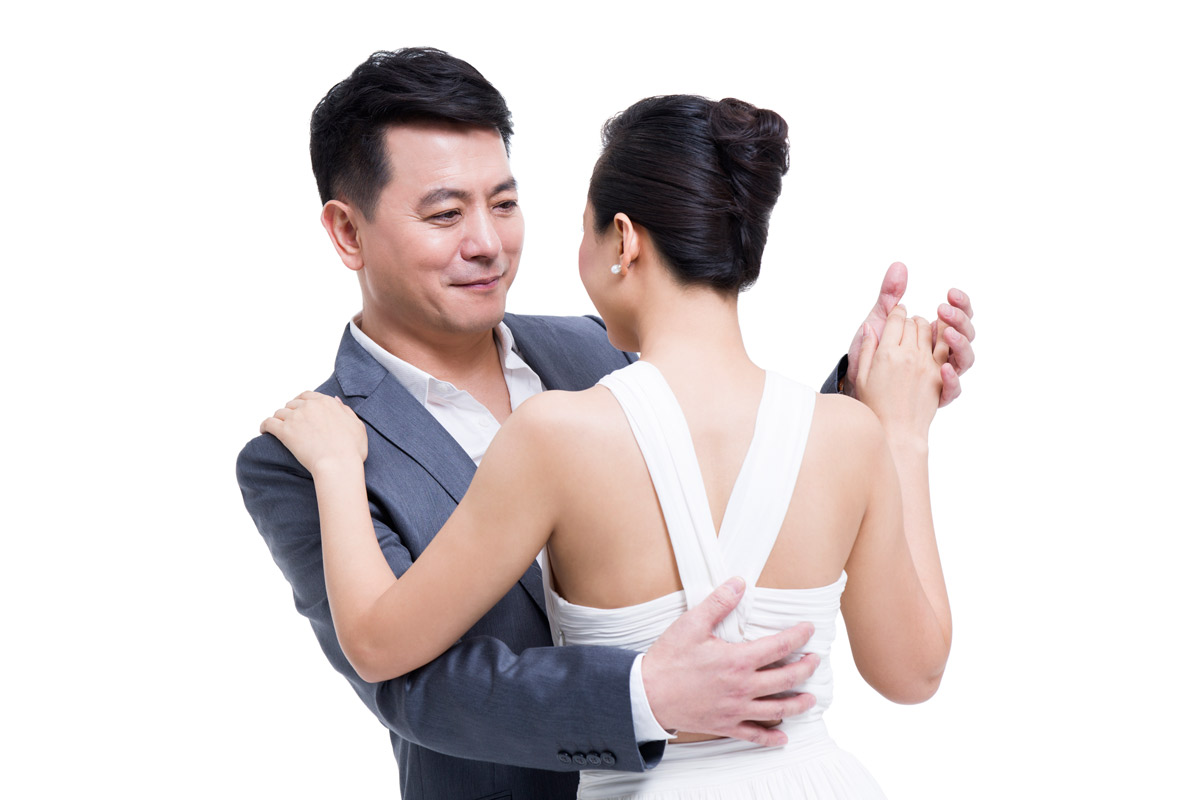 Asian bride and father holding hands and dancing while looking at each other