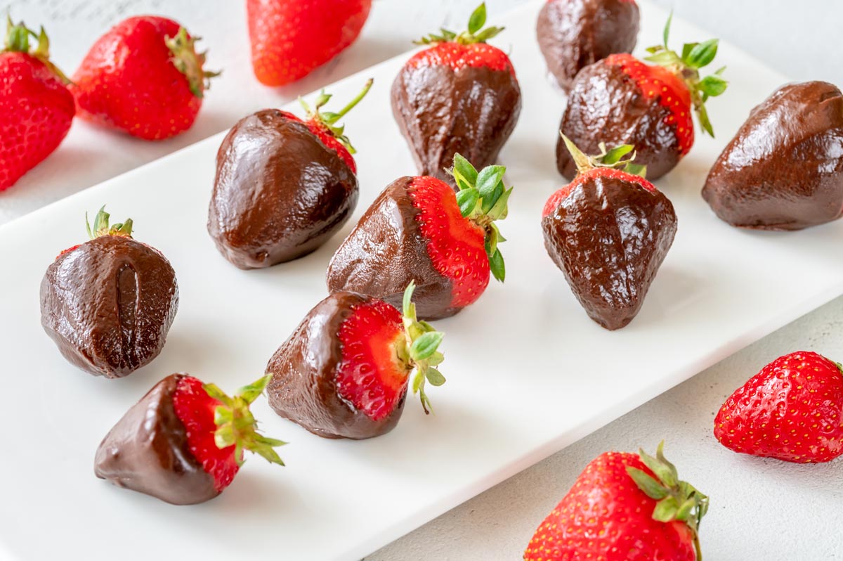 White rectangle plate of dark chocolate-covered strawberries for a healthy dessert option.