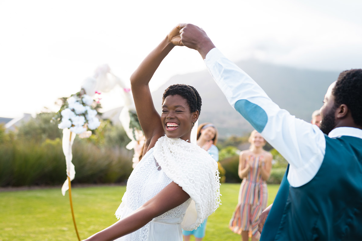 black bride dancing with her father in a green field and spun with one arm over head