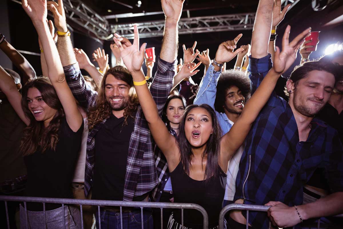 A bunch of people with their hands in the air being at a concert. 