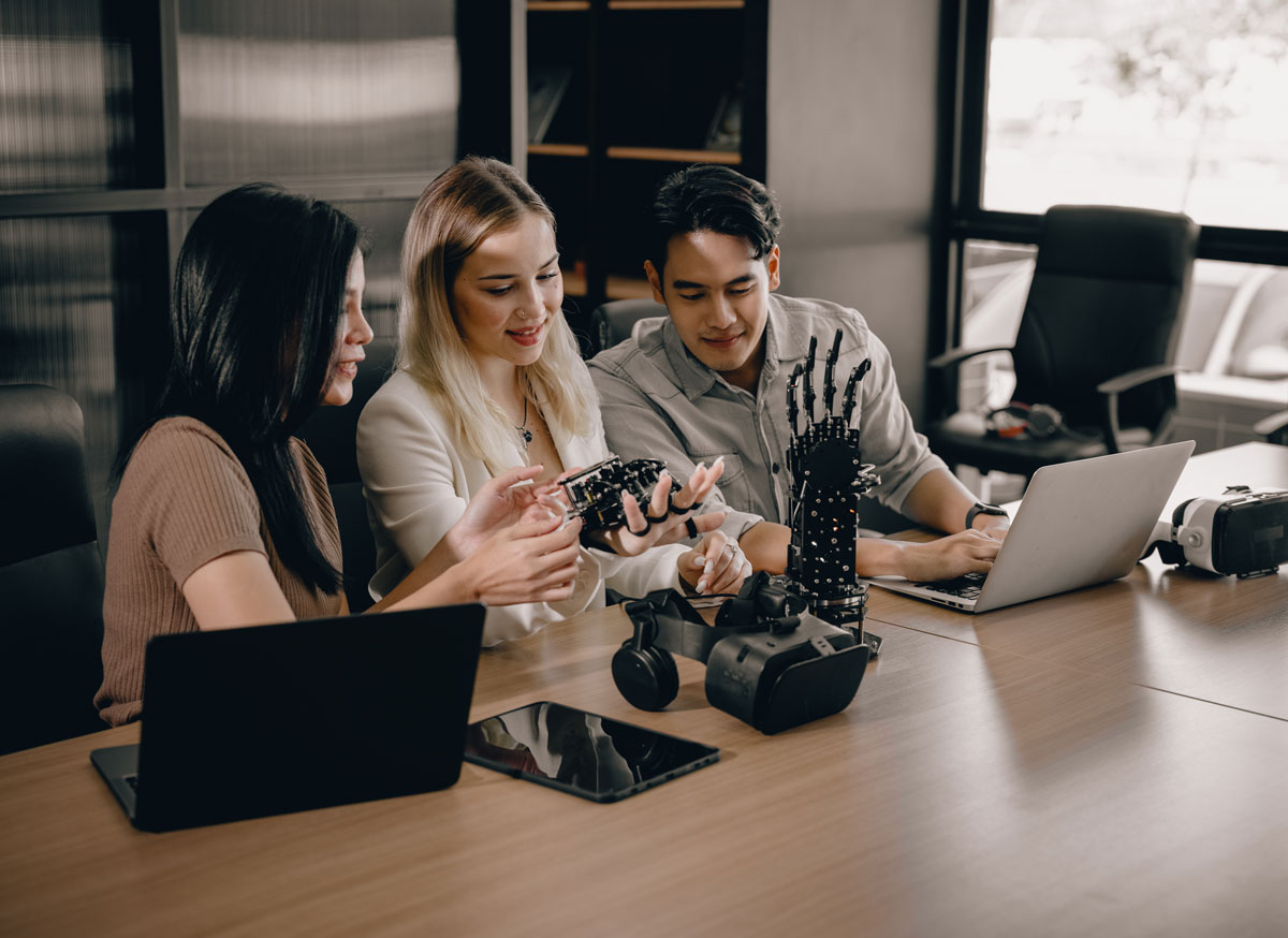 Two women and a man looking at technology in an office. 