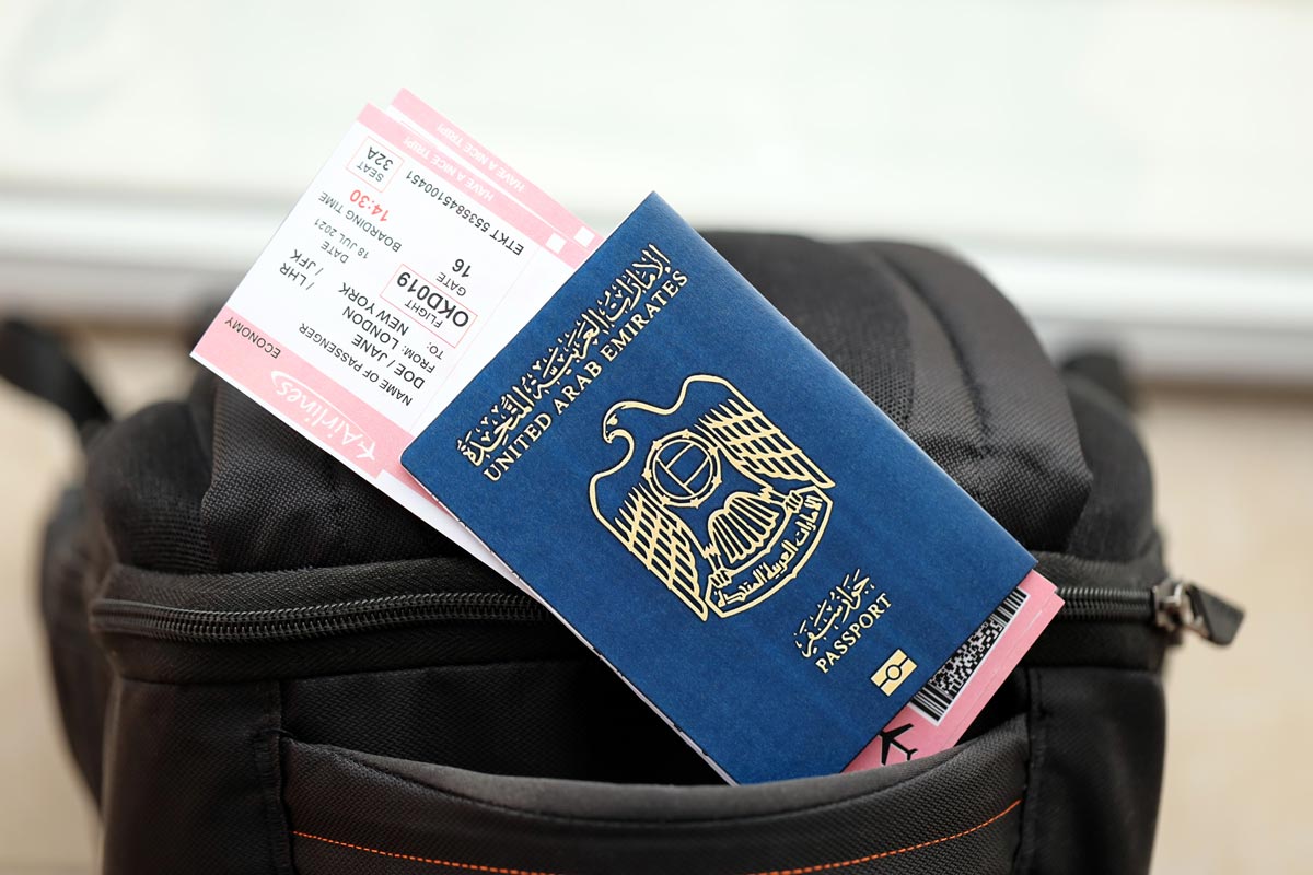 passport and plane tickets sticking out of black backpack