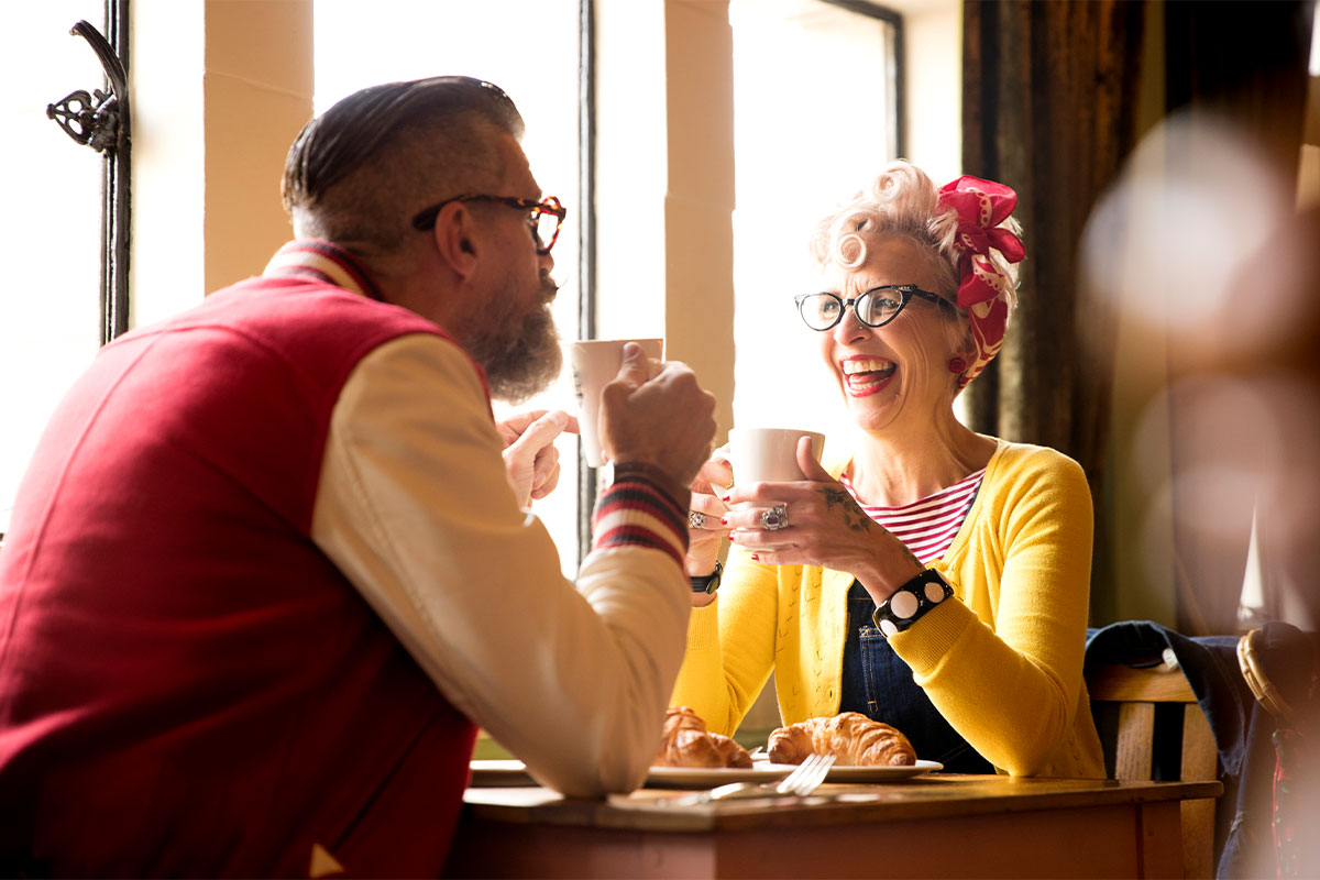 Quirky senior couple relaxing at a bar and restaurant with coffee cups 