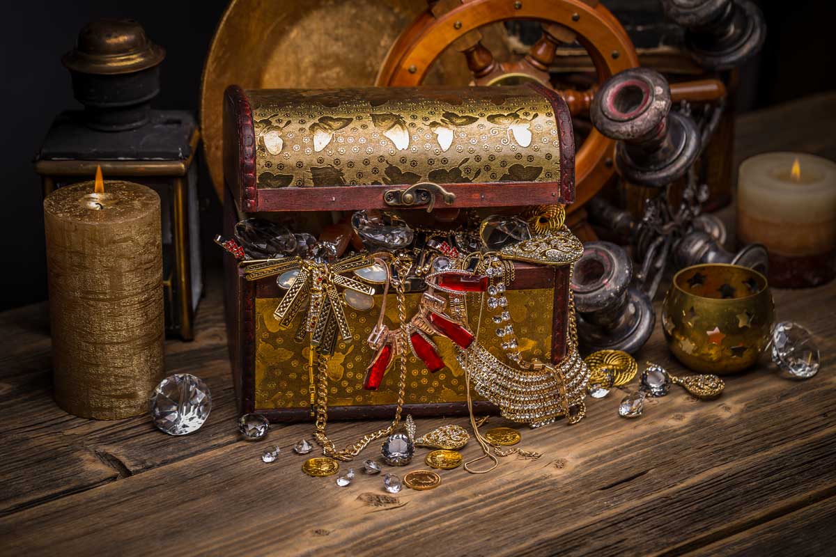 gold treasure chest filled with jewels on a wooden table. 