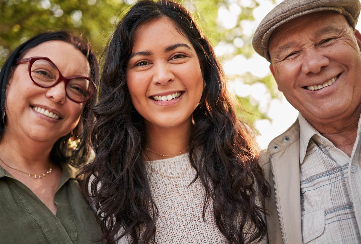  A 20 something hispanic woman standing with her grandparents smiling for a picture