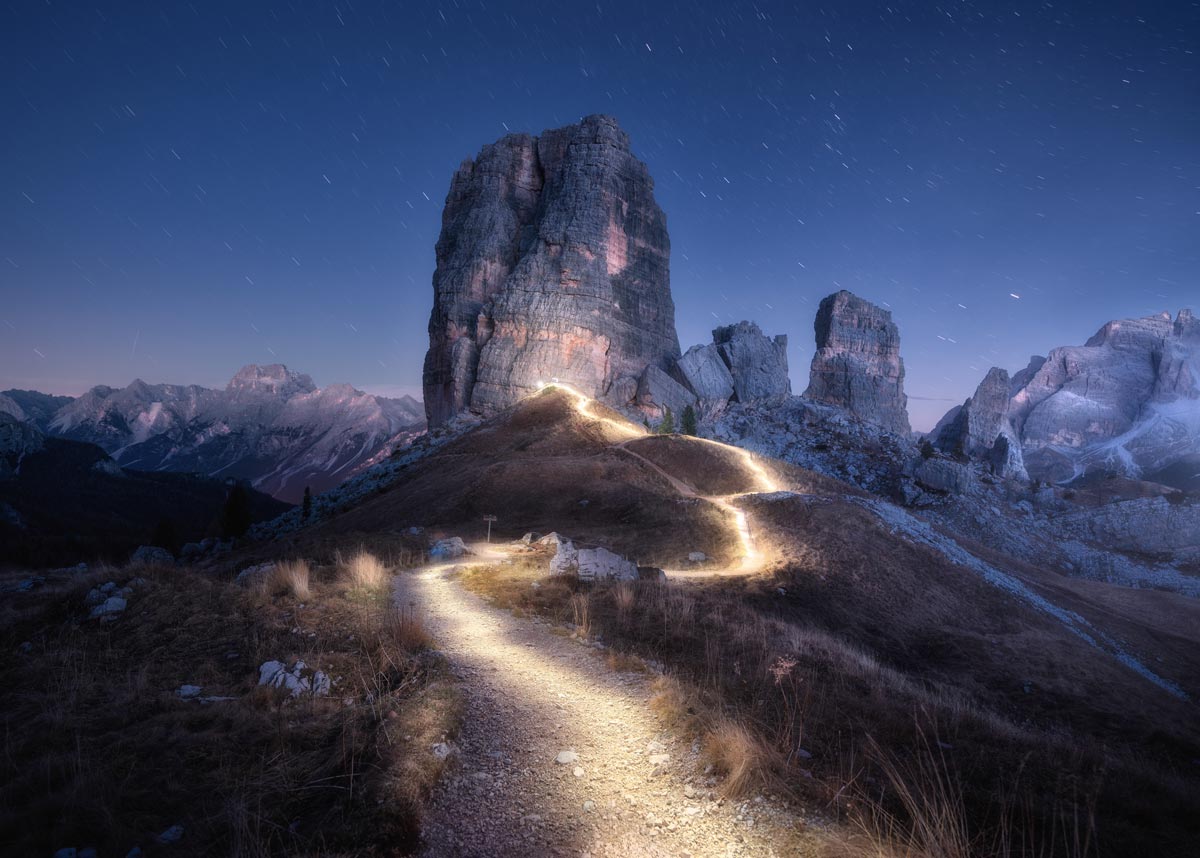 Trail on mountain glowing at night with stars. 