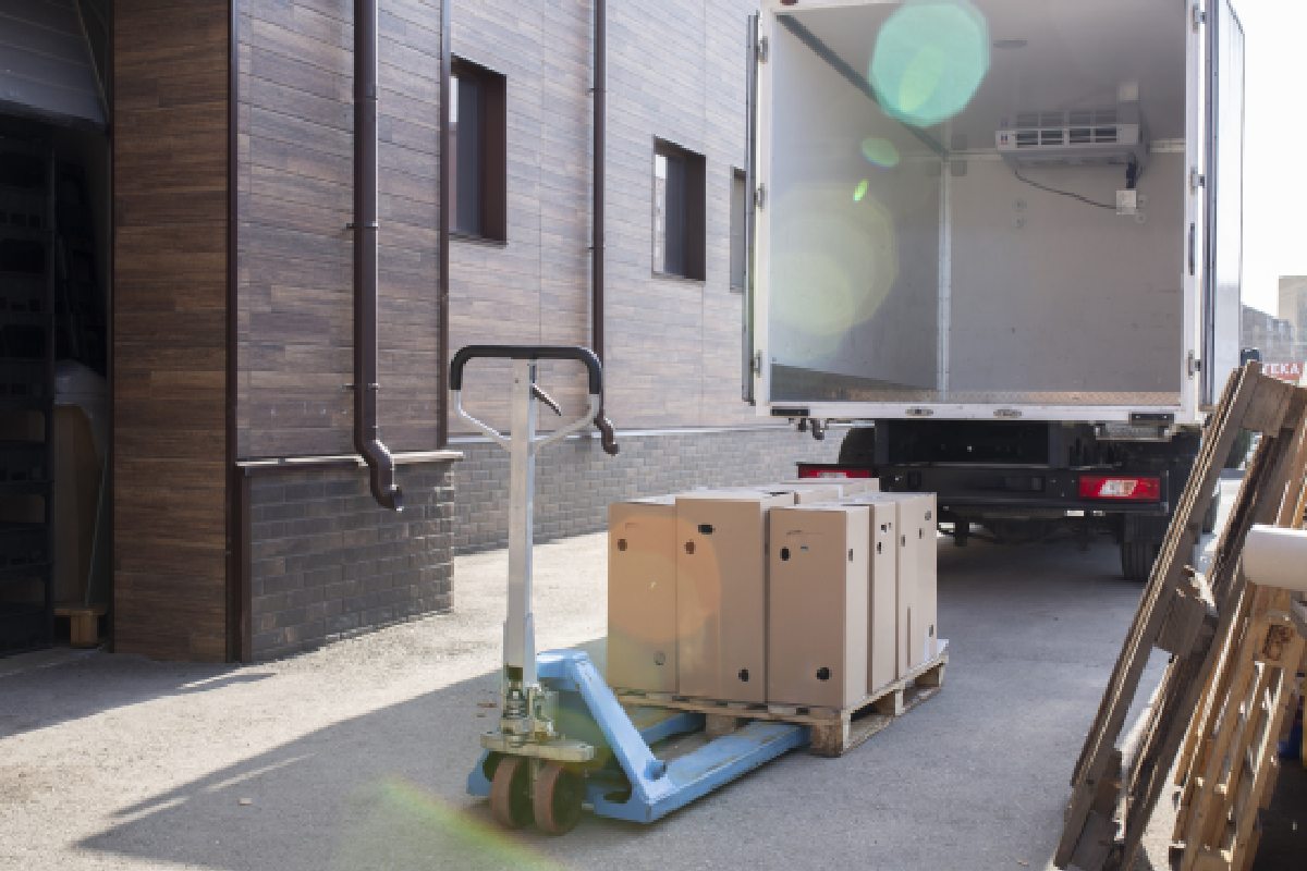 Empty moving truck at a loading dock with boxes on a pallet to move them.