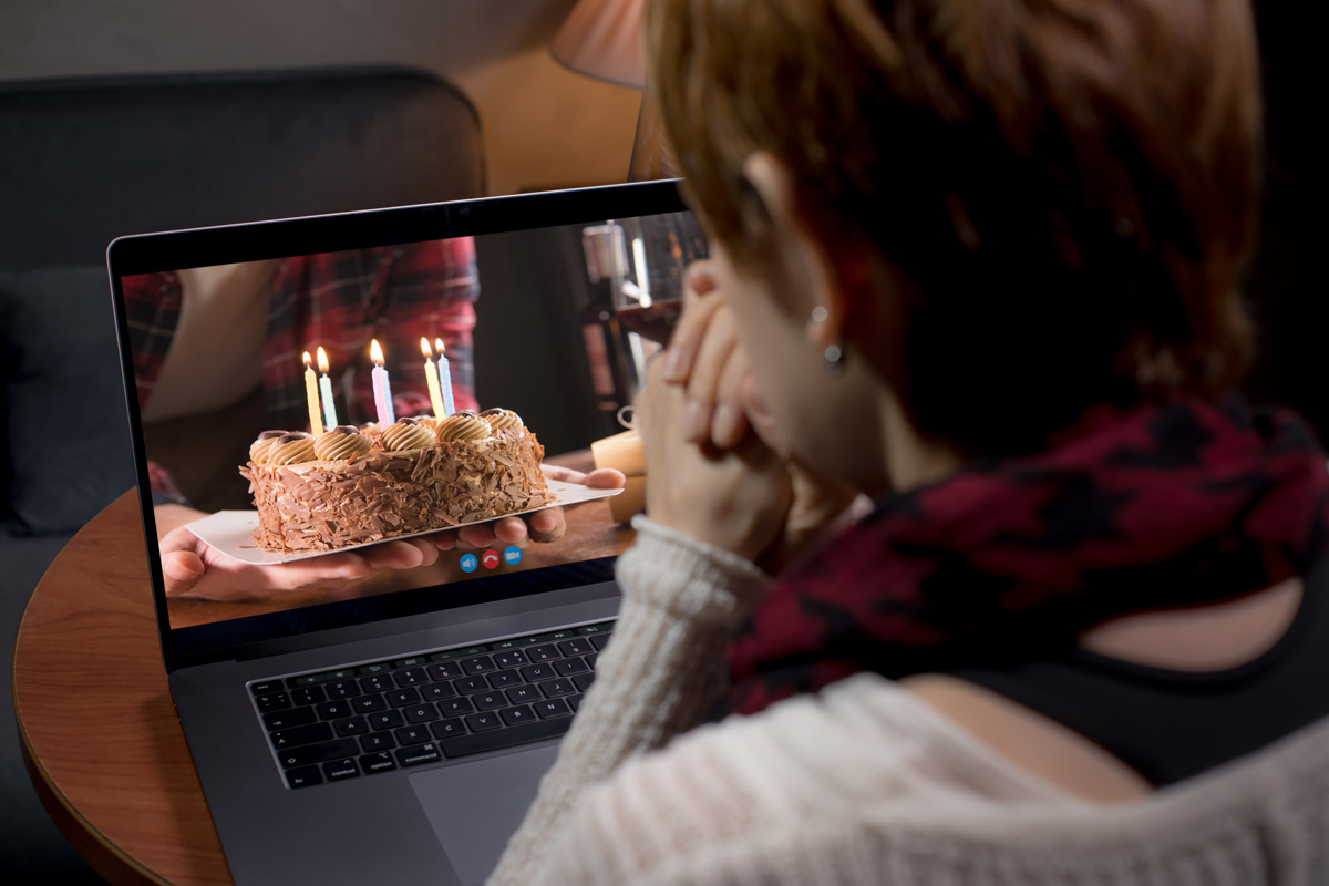 Women video chats with long-distance boyfriend on laptop for his birthday as he shows her his birthday cake