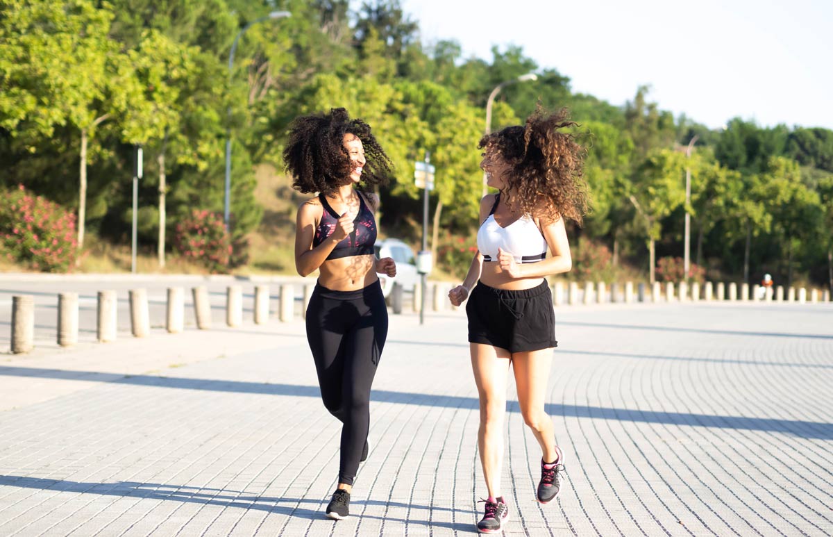 Two biracial women running and laughing next to each other