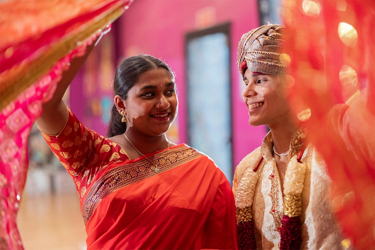 A Hindu couple in their 30s in traditional outfits smiling