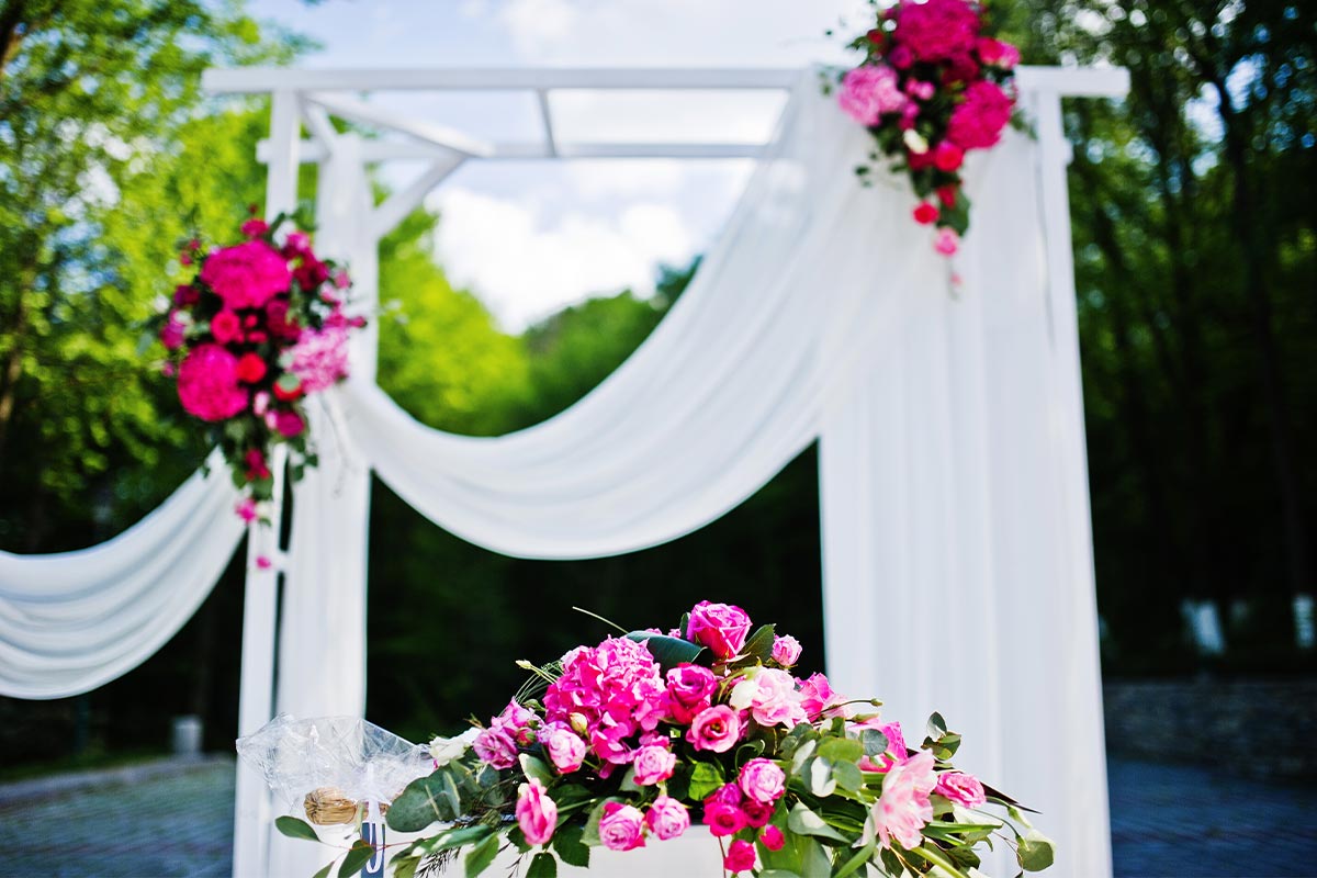 A white archway decorated with pink flowers