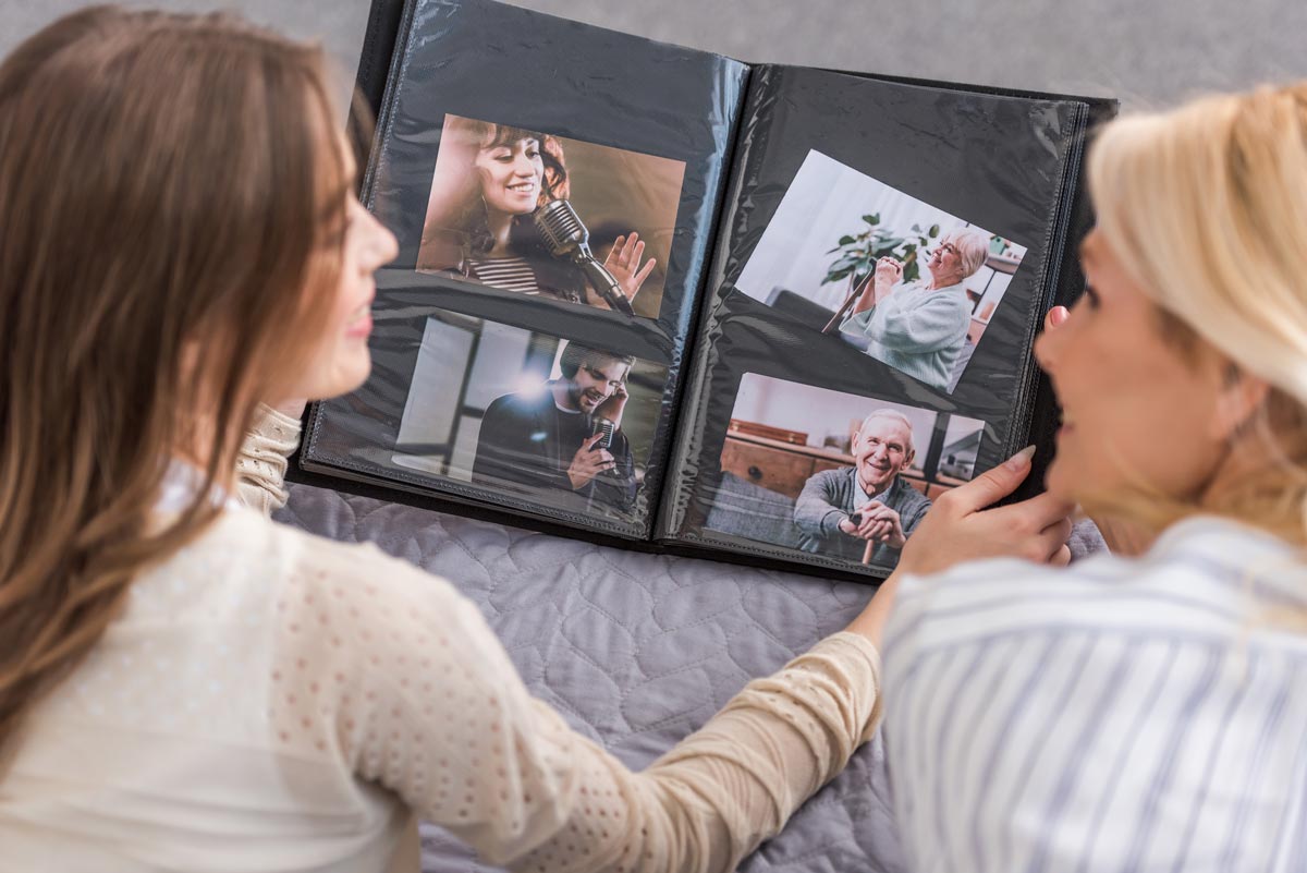 A late 20’s woman and an older woman above 50 looking through a photo album smiling together