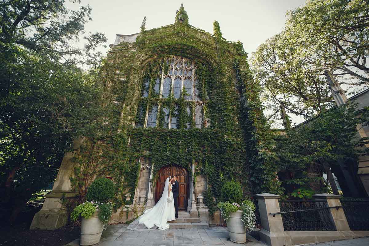  Elegant wedding couple embracing on their wedding day in front of vine-covered mansion