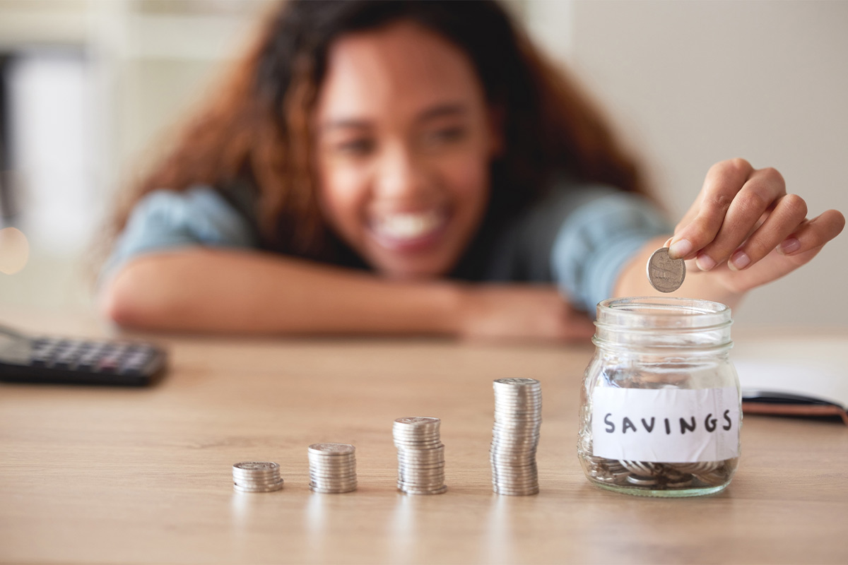 Black female puts her coins in a savings jar