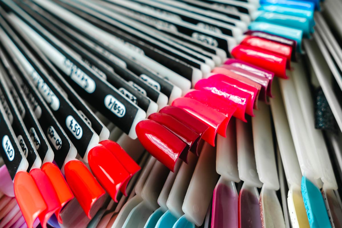 Multiple nail polish sample palettes displayed in a nail salon showing a wide range of color choices for clients.