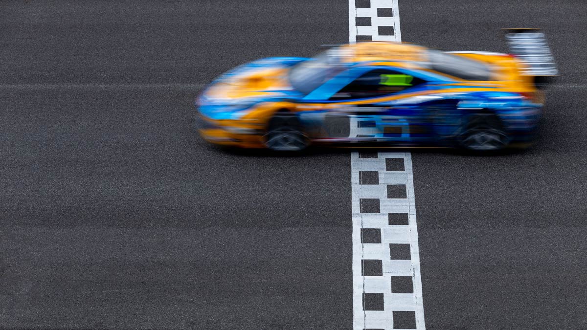 Blurry multicolored Racing car crossing finish line on racing track