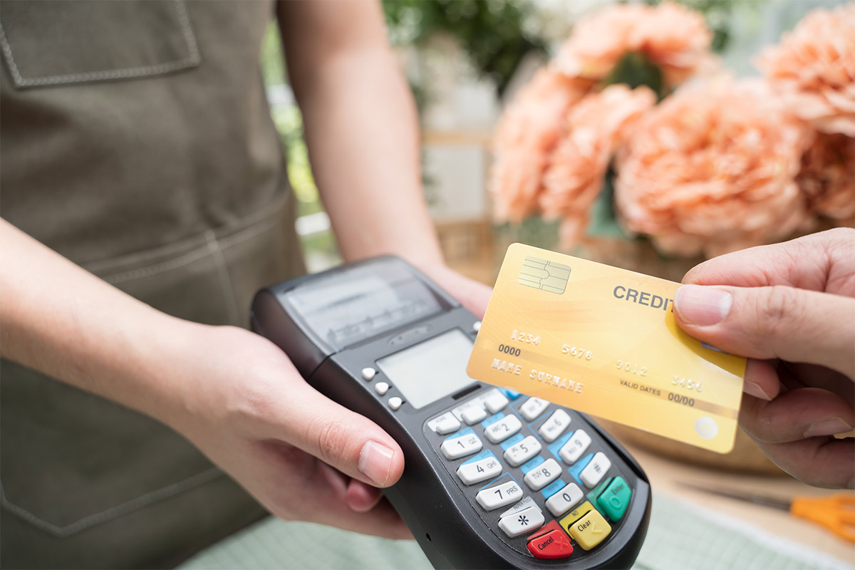 Hand of customer holding a credit card over a card reader device for payment