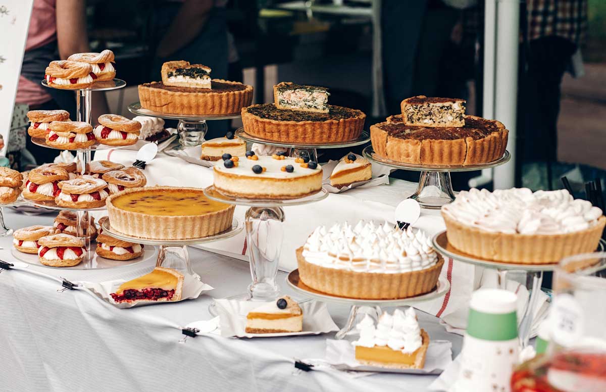 Wedding dessert table with a variety of pies topped with whipped cream, offering a classic dessert option.