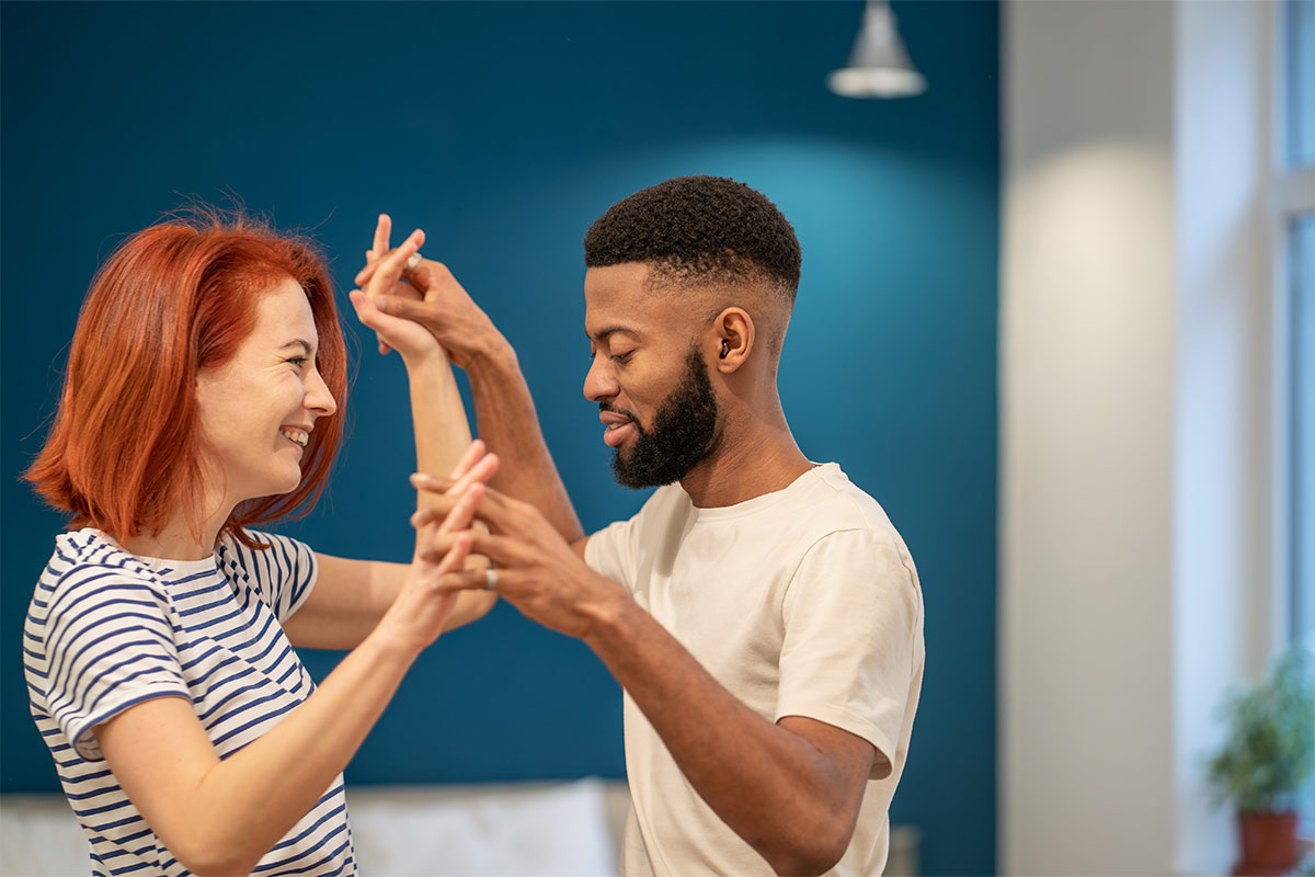 Young diverse couple practicing a romantic dance move in a well-lit indoor space showing the value of consistent practice for the first dance.