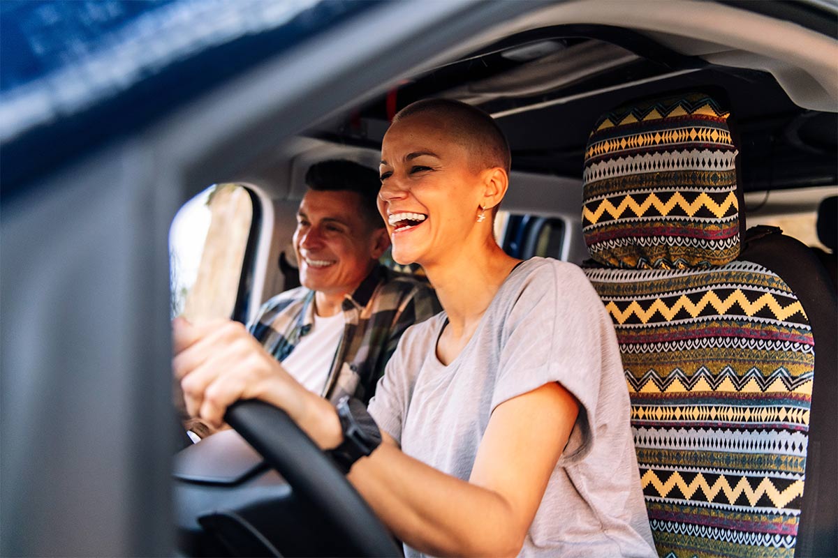 Happy 30 something couple laughing together during a camper van trip