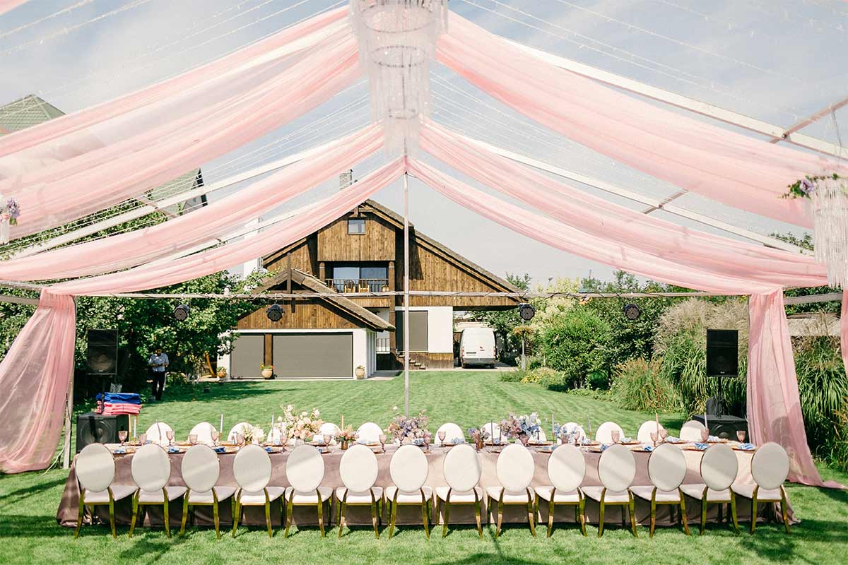 A pink tent over a long table with chairs outdoors