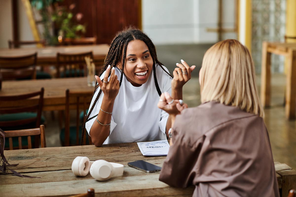 Two 20 something women black and white at a restaurant talking and smiling 