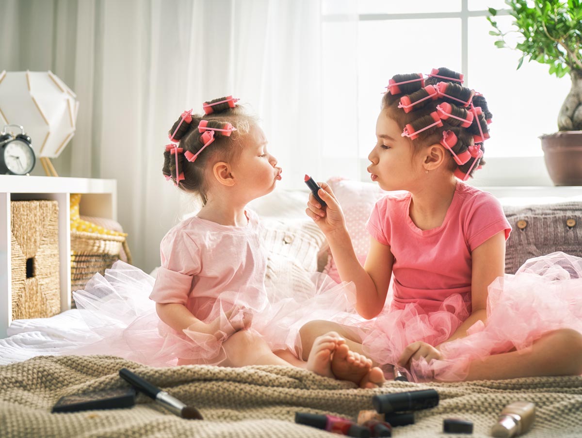 Two white little girls dressed in tutus playing with makeup