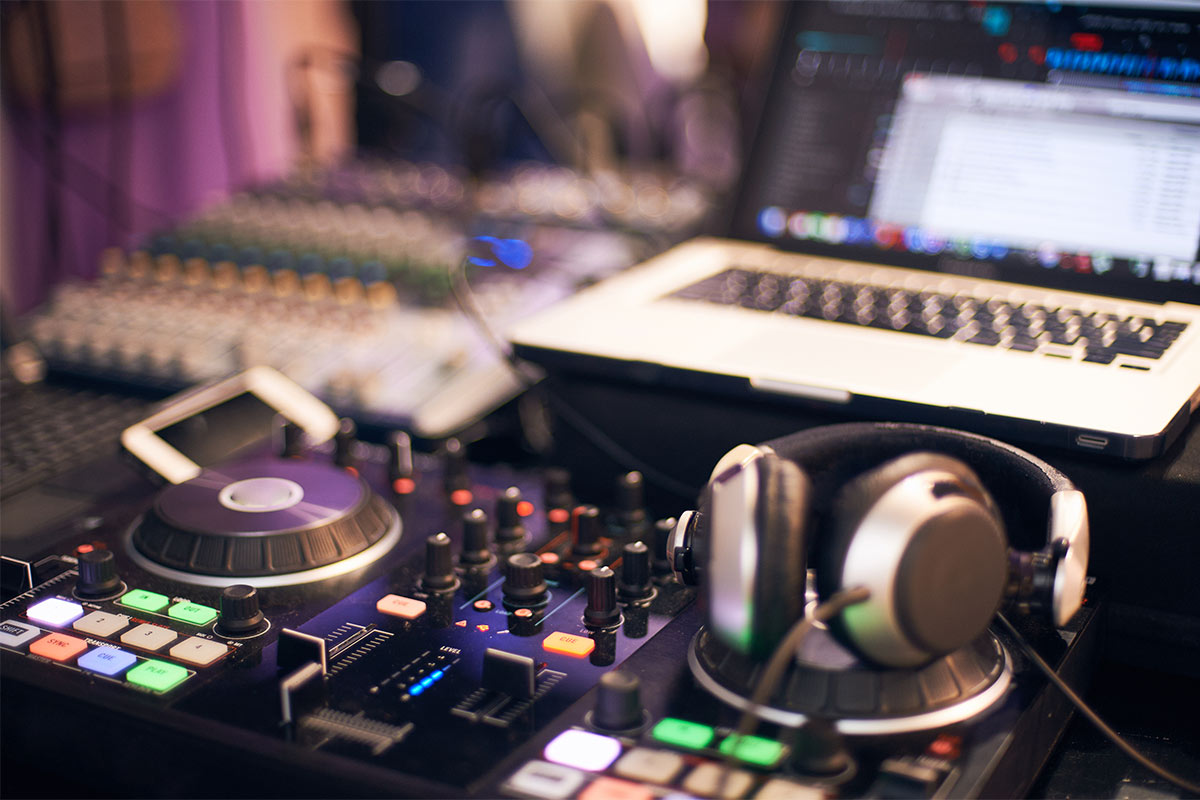 Professional DJ setup with a turntable, headphones, and laptop displaying a music database screen