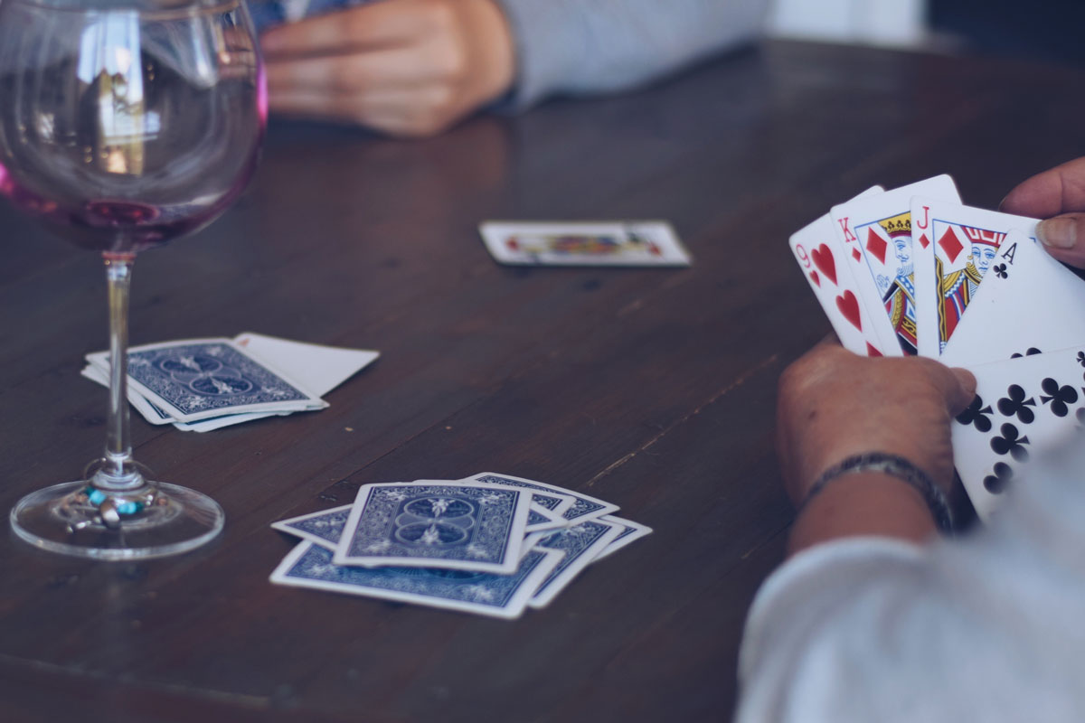 Group of people playing cards and with wine glasses at a table