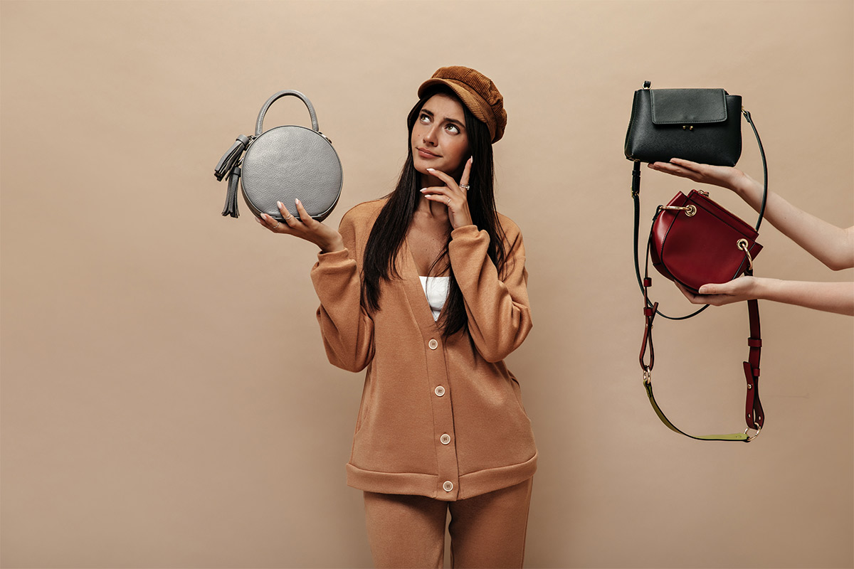  Mixed-race 26-year-old woman in an all brown outfit trying to decide which purse to use. 