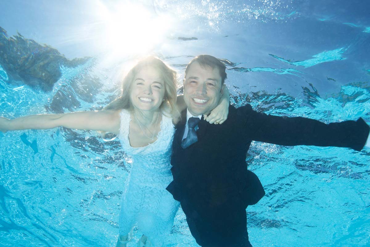 White 30 something bride and groom together underwater in wedding attire